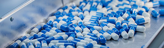 Blue Capsules are Moving on Conveyor at Modern Pharmaceutical Factory. Tablet and Capsule Manufacturing Process. Close-up Shot of Medical Drug Production Line.
