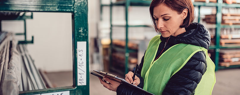 Female warehouse clerk signing document