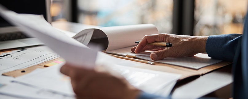 Cropped photo of man with pen in hand editing some paperwork at his office