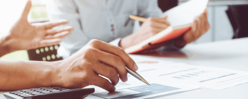 Two coworkers make plans for tariff savings at their desk while looking at a notebook